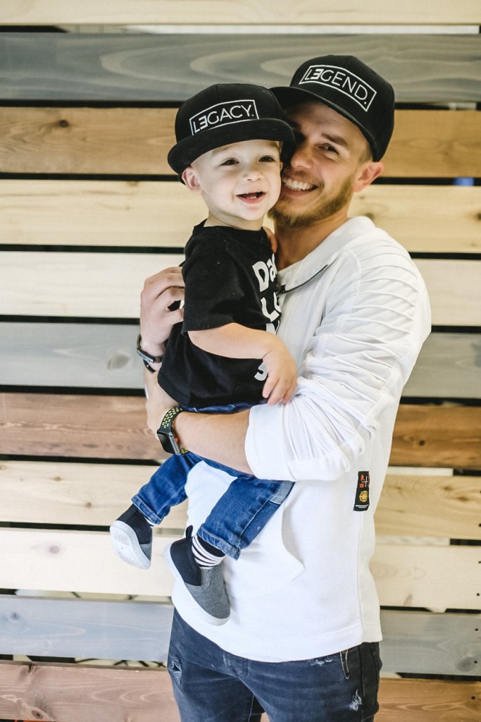 Father holding son in his arms wearing matching hats - Becoming A Dad - The Pause Pursuit